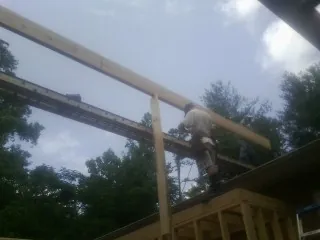 Carpenter setting a ridge beam over a new addition frame — Ice Dam Removal by Roofing Brothers in Satartia