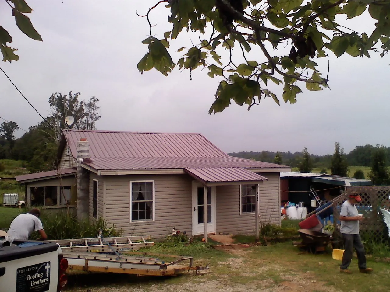 Crew finishing a mauve metal roof on a small farmhouse in Satartia