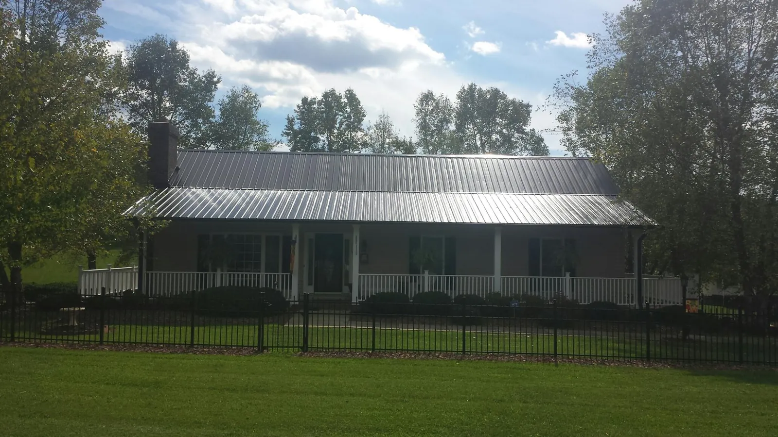 Gray metal roof on a brick ranch with a full width front porch — Gutter Guard Installation work by our crew in Satartia
