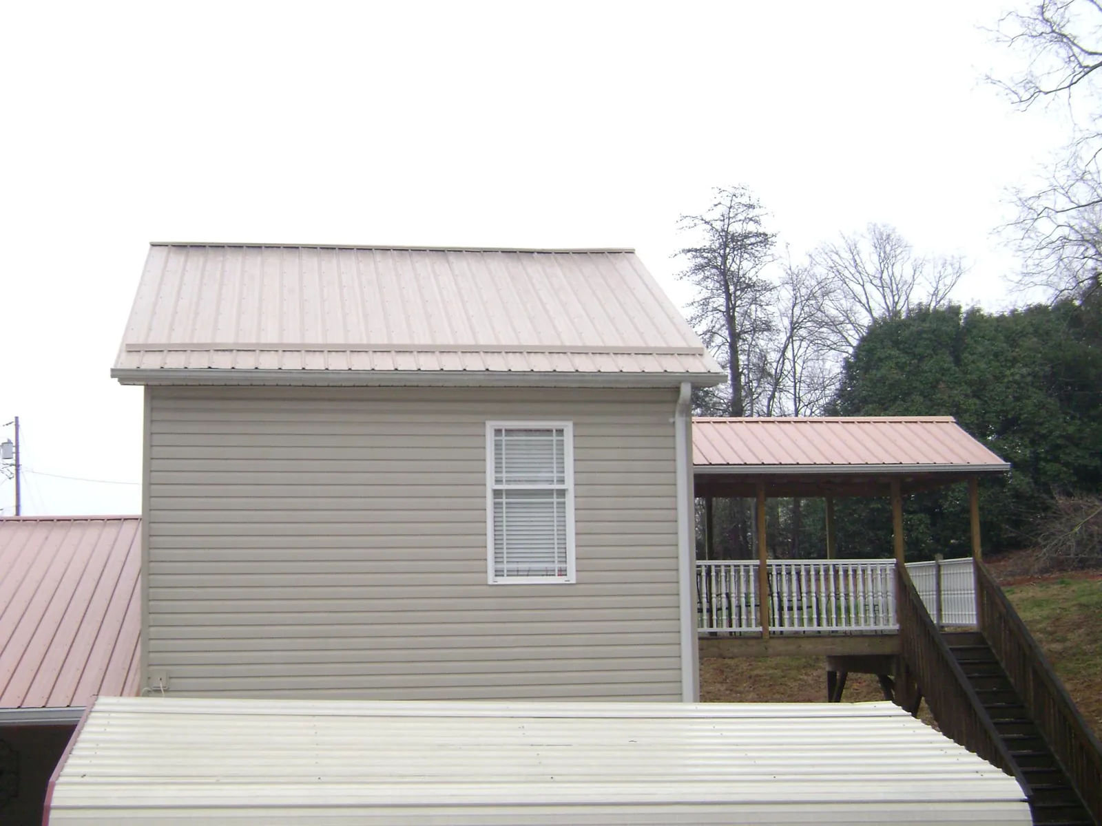Tan metal roofs on a two story addition and attached porch, from a Roof Replacement job in Satartia