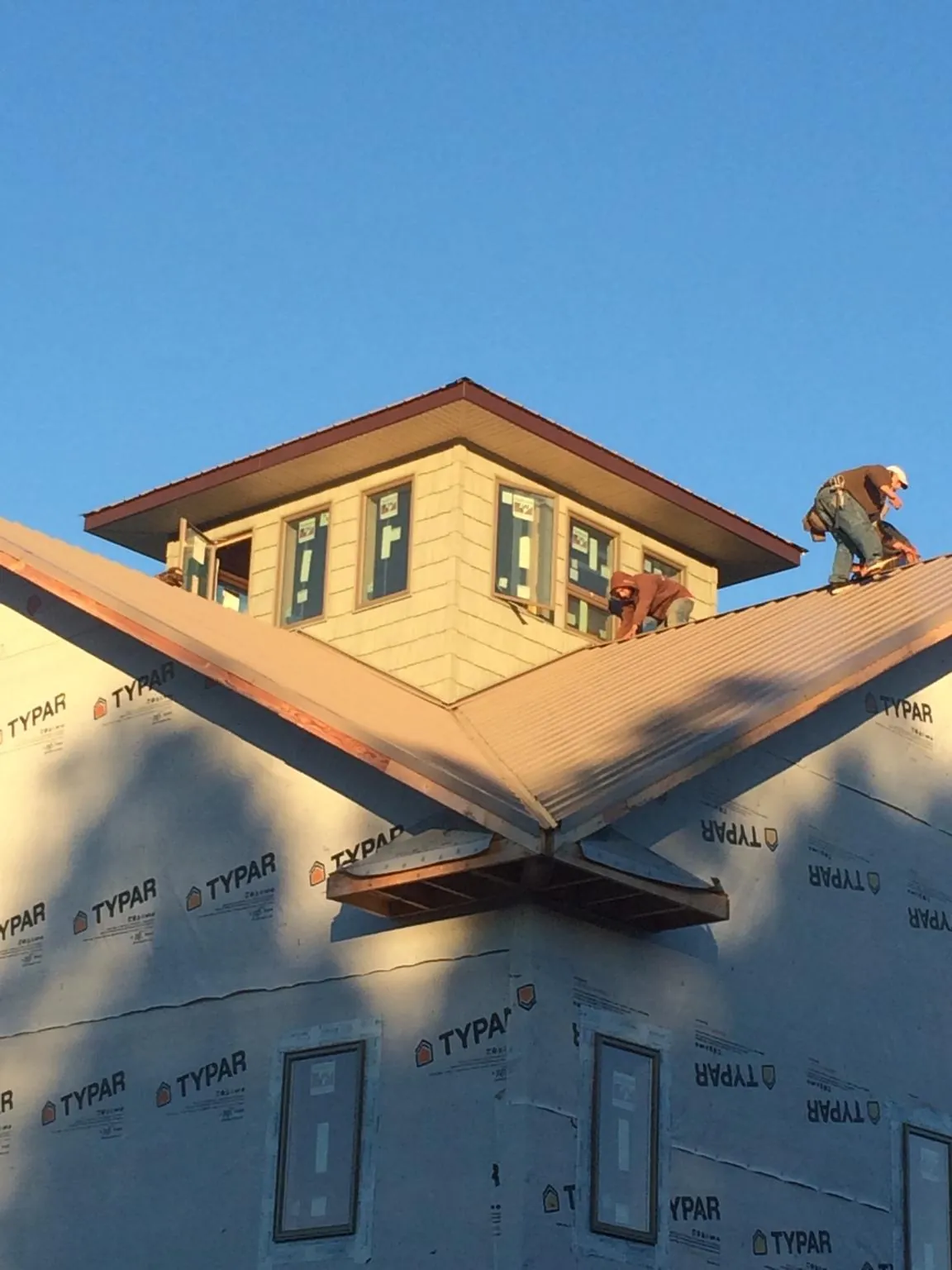 Roofers working around a rooftop cupola on a new metal roof at sunset — Roof Waterproofing in Satartia by Roofing Brothers